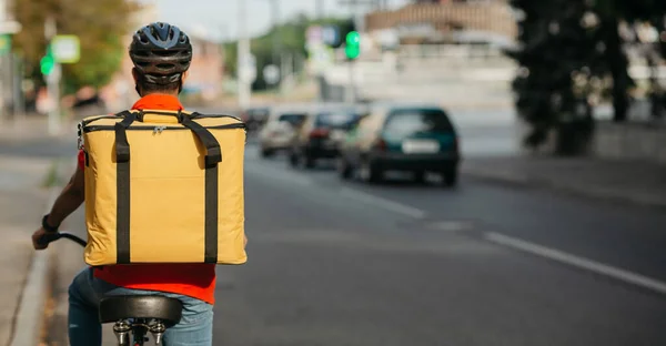 Entrega rápida moderna na cidade. Jovem de capacete com mochila anda de bicicleta na estrada — Fotografia de Stock