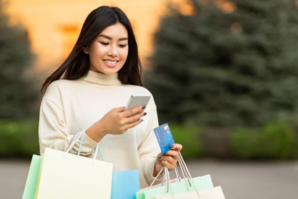 Asiatisk flicka med kreditkort och telefon nära centrum — Stockfoto