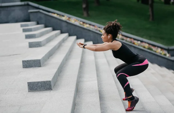 Zayıflama egzersizi. Kablosuz kulaklık ve spor takip cihazıyla merdivenlerden atlayan Afro-Amerikan kız. — Stok fotoğraf