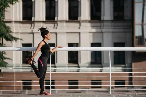 Yazın şehirde spor. Afrikalı Amerikalı kız bacak egzersizi yapıyor. — Stok fotoğraf