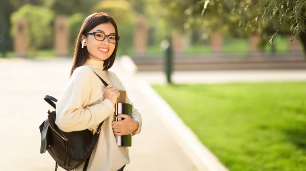 Chica en gafas y auriculares de pie en el parque — Foto de Stock