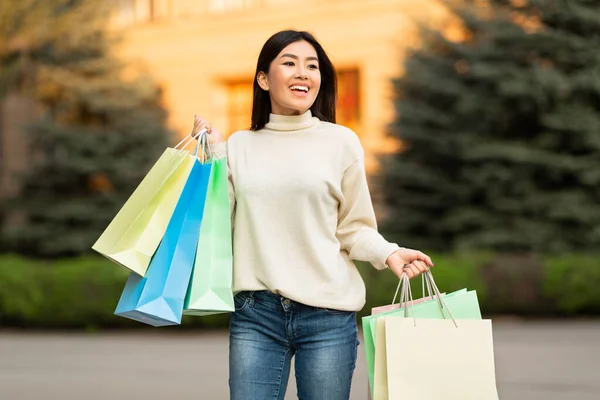 Asiatisk flicka med shoppingväskor nära centrum — Stockfoto