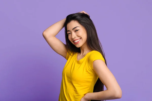 Retrato de beleza de menina coreana sorridente tocando seu cabelo sobre fundo roxo — Fotografia de Stock