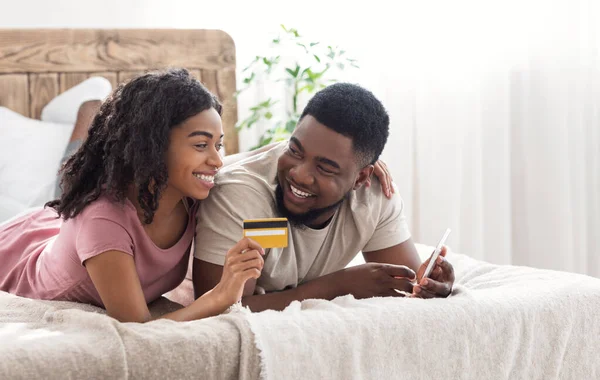 Africano casal feliz compra on-line, usando smartphone e cartão de crédito — Fotografia de Stock