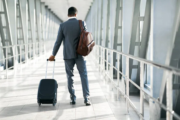Uomo d'affari afroamericano a piedi di nuovo alla macchina fotografica in aeroporto all'aperto — Foto Stock