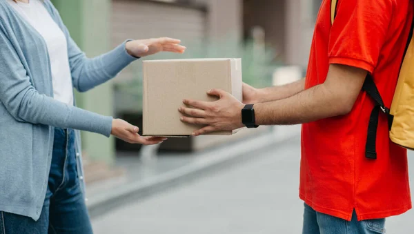 Usługi kwarantanny i dostawy online. Kobieta przyjmuje paczkę od kuriera z inteligentnym zegarkiem i plecakiem — Zdjęcie stockowe