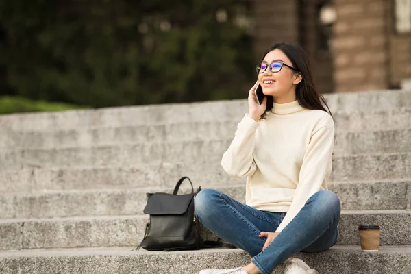 Жінка-студент, що використовує телефон, сидить на кроках — стокове фото