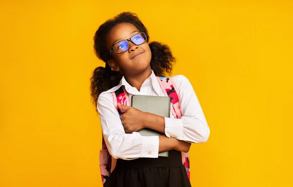 Happy African Schoolgirl Memeluk Buku Selama Latar Belakang Studio Kuning — Stok Foto
