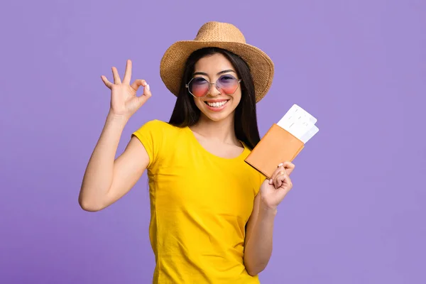 Buon viaggio. Gioioso asiatico donna con passaporto e biglietti gesturing ok segno — Foto Stock