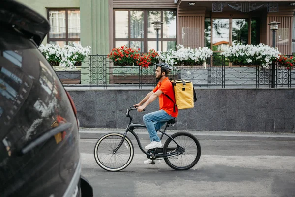 Correio do dia de trabalho na cidade. Jovem em capacete de segurança com mochila passeios de bicicleta na estrada — Fotografia de Stock