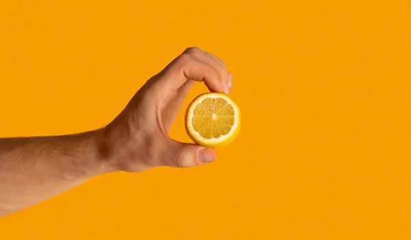 Jovem mostrando frutas de limão cortadas sobre fundo laranja, close-up com espaço para texto — Fotografia de Stock