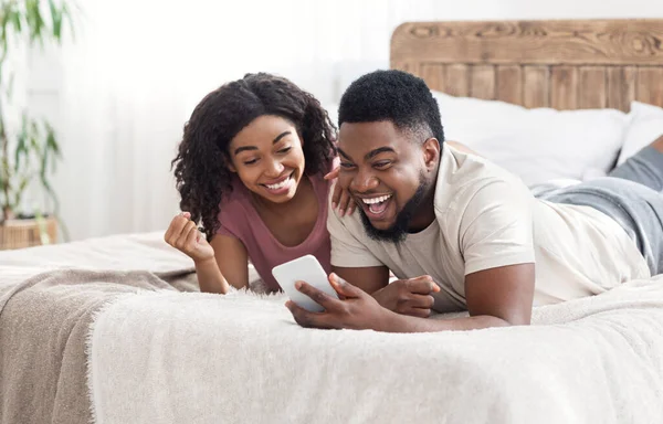 Gelukkig zwart liefhebbers vieren succes, het houden van smartphone — Stockfoto