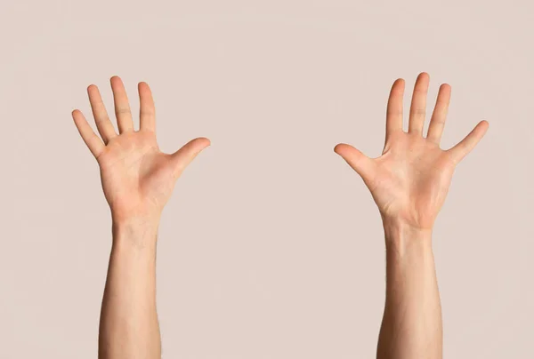 Millennial muž zvedá obě ruce na světlém pozadí, detailní záběr — Stock fotografie