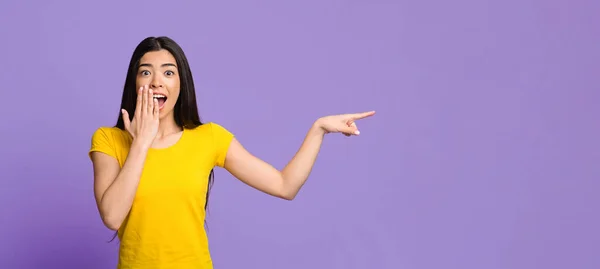 Schokkend aanbod. Opgewonden aziatische vrouw wijzen terzijde bij kopiëren ruimte met vinger — Stockfoto