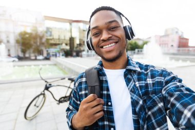 Heyecanlı Afrikalı Amerikalı adam bisikletiyle selfie çekiyor.