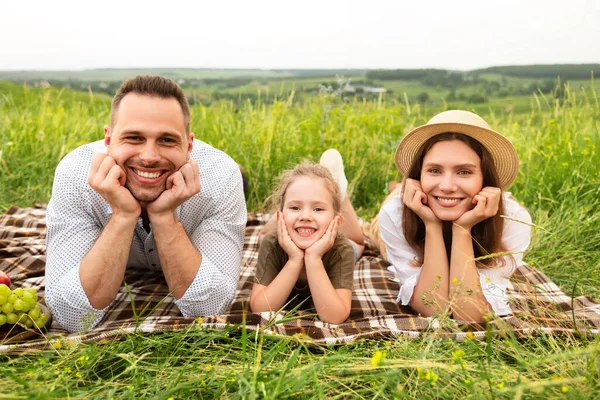 Feliz familia joven y encantadora pasando tiempo juntos en un picnic — Foto de Stock