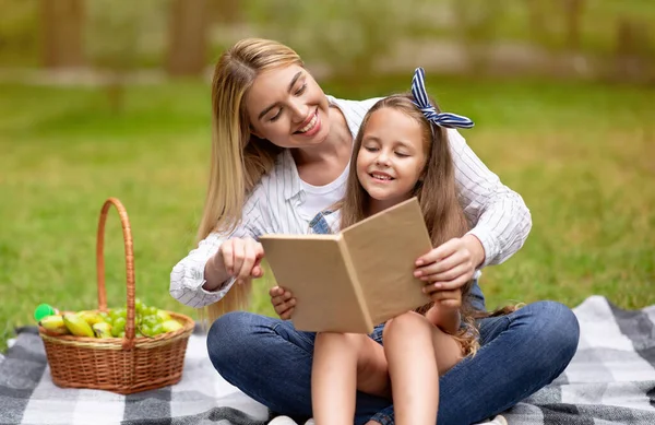 Mamma och dotter läser bok i parken spendera tid tillsammans — Stockfoto