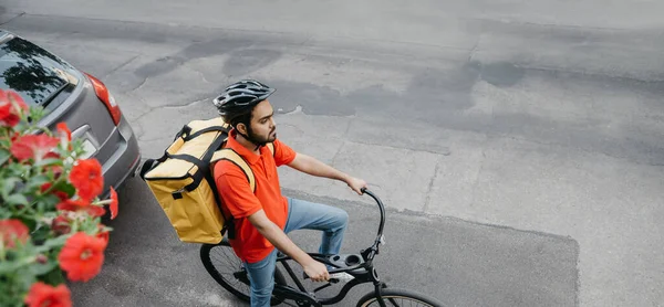 Serviço de entrega online. Courier em capacete com grande mochila amarela na bicicleta — Fotografia de Stock