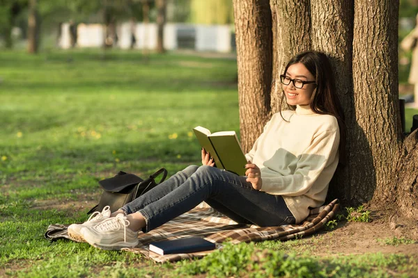 Дівчина читає книгу, що сидить під деревом — стокове фото