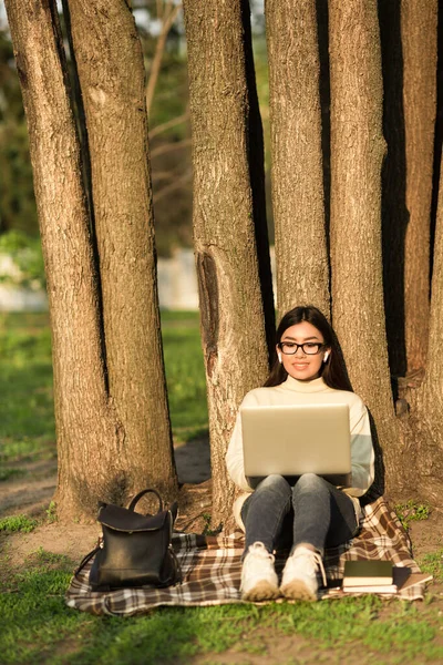 Ženské studentky pomocí notebooku, sedí v parku — Stock fotografie