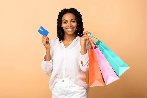 Svart kvinna innehar kreditkort och shoppingväskor, Beige bakgrund — Stockfoto