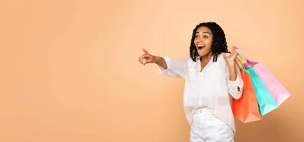 Negro chica en compras señalando dedo aparte posando en estudio —  Fotos de Stock