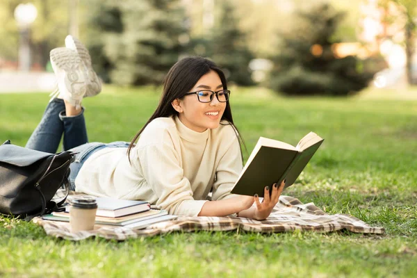 Дівчина читає роман, що сидить під деревом — стокове фото