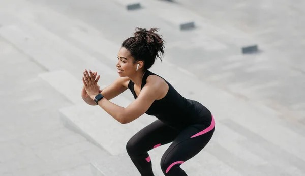 Esercizi per gambe e glutei. Donna in forma sorridente con bel corpo e gadget, accovacciato — Foto Stock