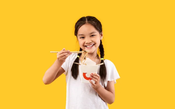 Asiática chica comiendo fideos de caja usando palillos, Studio Shot — Foto de Stock