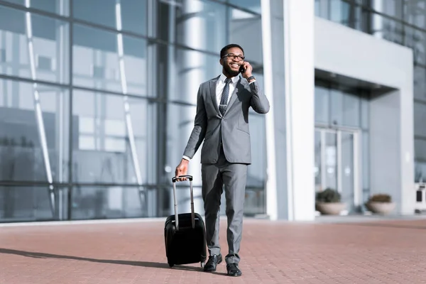 Hombre de negocios africano feliz charlando por teléfono llegando al aeropuerto, de larga duración — Foto de Stock