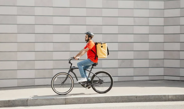 Müşteriye giden yol. Sırt çantalı genç adam bisiklete biniyor. — Stok fotoğraf