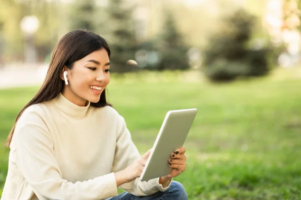 Donna asiatica studente utilizzando tablet, seduto nel parco — Foto Stock