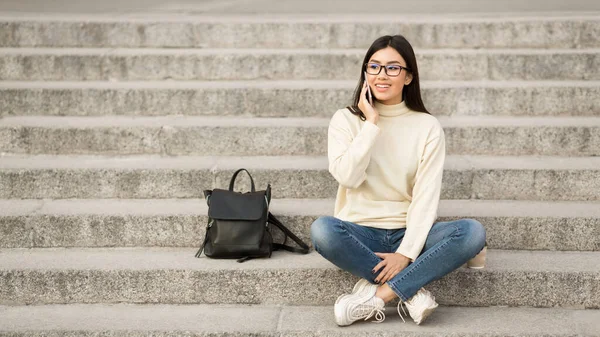 Joven estudiante usando el teléfono, sentada en los escalones — Foto de Stock