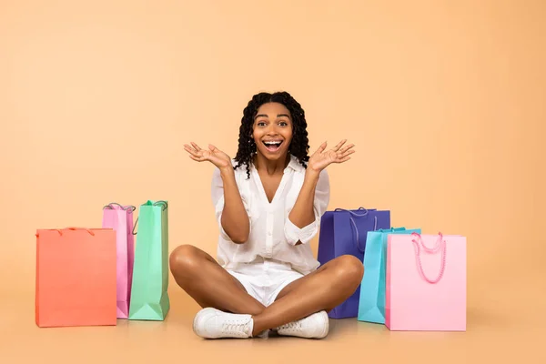 Černá dívka sedí mezi nákupními taškami křičí vzrušení, Studio — Stock fotografie