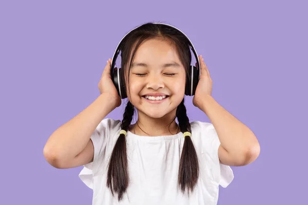 Menina coreana em fones de ouvido ouvir música, fundo roxo — Fotografia de Stock