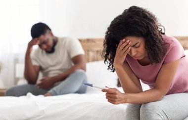 Pozitif hamilelik testi olan üzgün Afrikalı kadın ve erkek