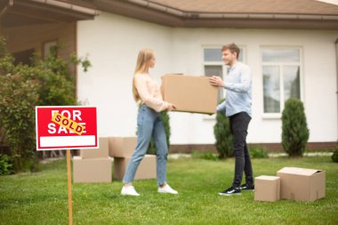 Taşındıkları gün yeni evlerinin önünde kutu taşıyan milenyum çifti, satış tabelasına odaklanıyor. Boşluğu kopyala
