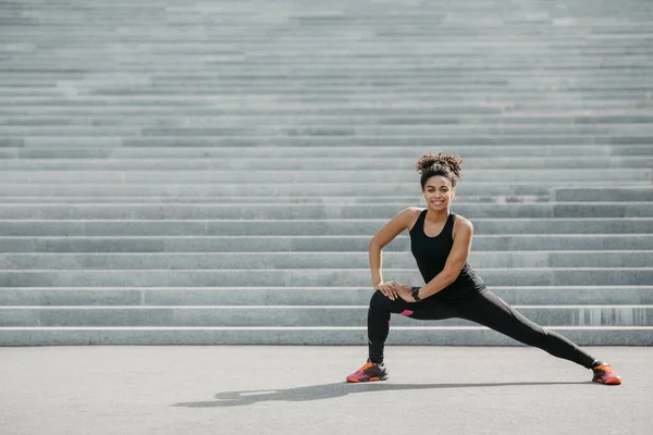 Jovem e treino ativo na rua. Menina em sportswear com rastreador de fitness faz exercícios em escadas — Fotografia de Stock
