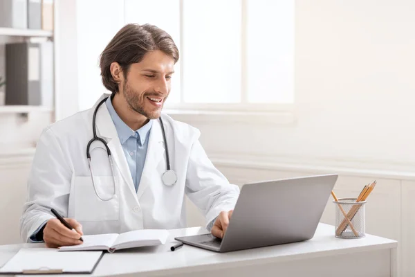 Joven médico conversando con sus colegas a través de ordenador portátil en línea — Foto de Stock