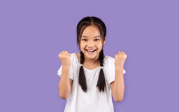 中国小女孩为庆祝紫色背景下的胜利而举手投足 — 图库照片