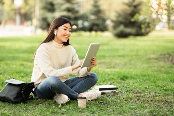 Öğrenci tablet kullanıyor, parkta oturuyor. — Stok fotoğraf