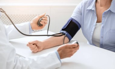 Doktor, yaşlı hasta için kan basıncını ölçüyor.