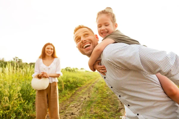 Cheerful dad piggybacking his little baby in countryside — Stock Photo, Image