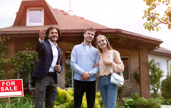 Joyeux couple marié rencontrant courtier immobilier à regarder la maison à vendre, à l'extérieur — Photo