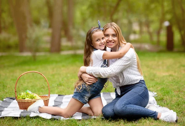 Happy Mother and Daughter Hugging Seitting On Plaid In Park — Stock fotografie