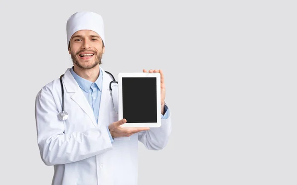 Giovane medico positivo che mostra tablet digitale con schermo vuoto — Foto Stock
