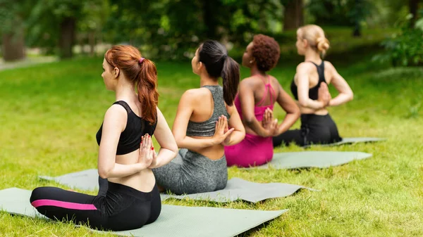 Women practicing yoga with namaste behind their backs at park, empty space — Stock Photo, Image