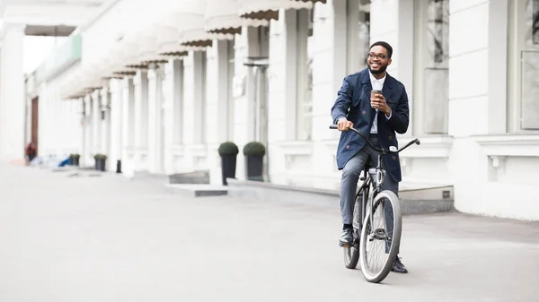 Bonito empresário afro andando de bicicleta bebendo chá — Fotografia de Stock