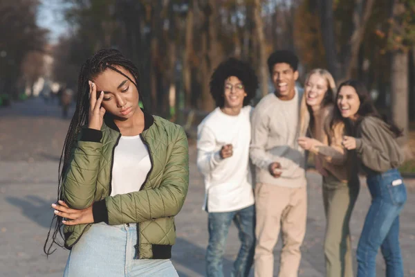 Upprörd tonåring flicka med vänner skvallrar i bakgrunden — Stockfoto