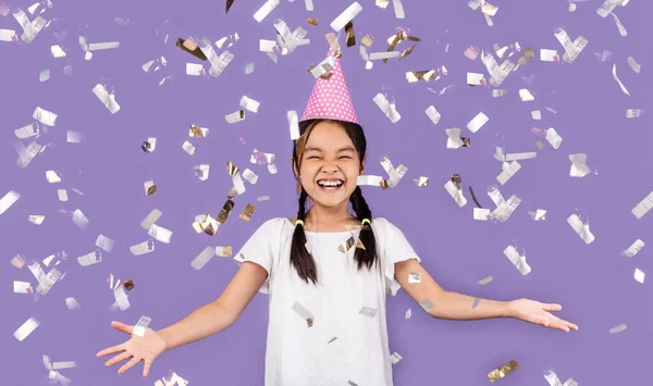 Fröhliches Geburtstagskind steht unter fallendem Konfetti, lila Hintergrund — Stockfoto